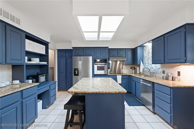 kitchen featuring appliances with stainless steel finishes, a sink, a breakfast bar area, visible vents, and blue cabinets
