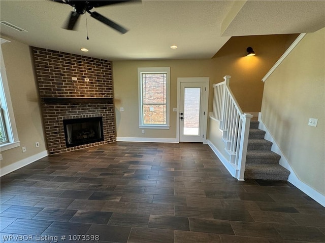 unfurnished living room featuring ceiling fan, dark hardwood / wood-style flooring, and a brick fireplace