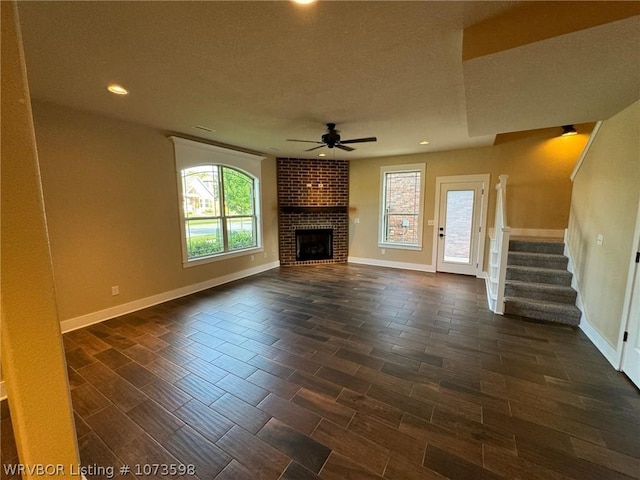 unfurnished living room featuring ceiling fan and a fireplace