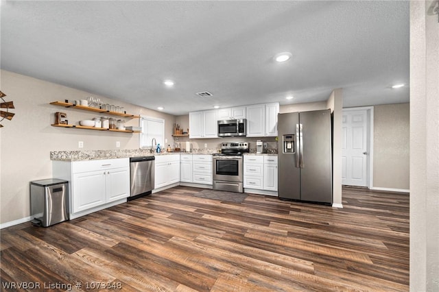 kitchen with sink, a textured ceiling, appliances with stainless steel finishes, dark hardwood / wood-style flooring, and white cabinetry