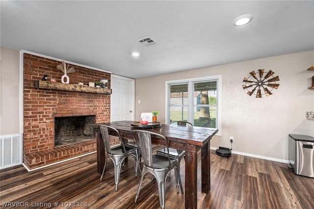 dining space with dark wood-type flooring and a brick fireplace