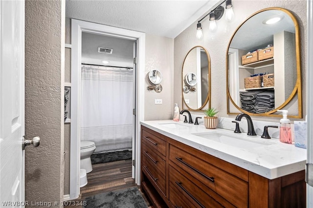 bathroom featuring a shower with curtain, a textured ceiling, vanity, hardwood / wood-style flooring, and toilet