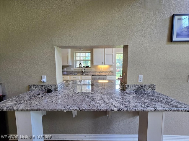 20222 Garman Rd, Gentry, AR 72734 - kitchen with a peninsula, a textured wall, white cabinetry, and stone countertops