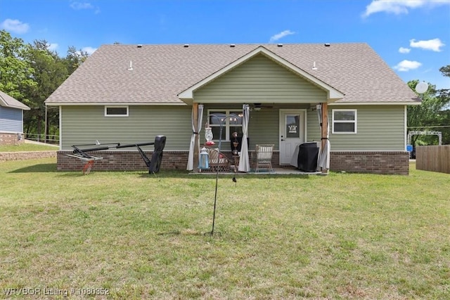 rear view of house featuring fence, brick siding, and a yard