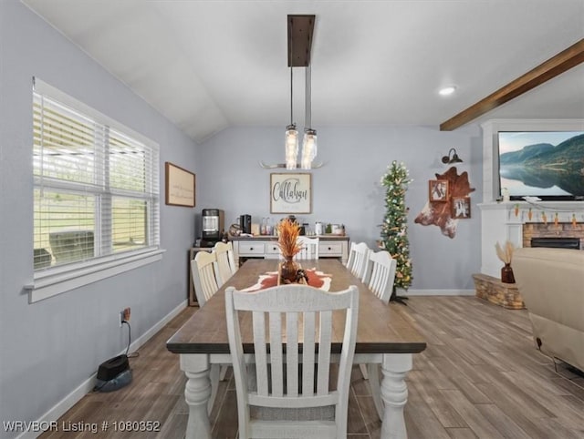 dining area with a fireplace, wood finished floors, lofted ceiling, and baseboards