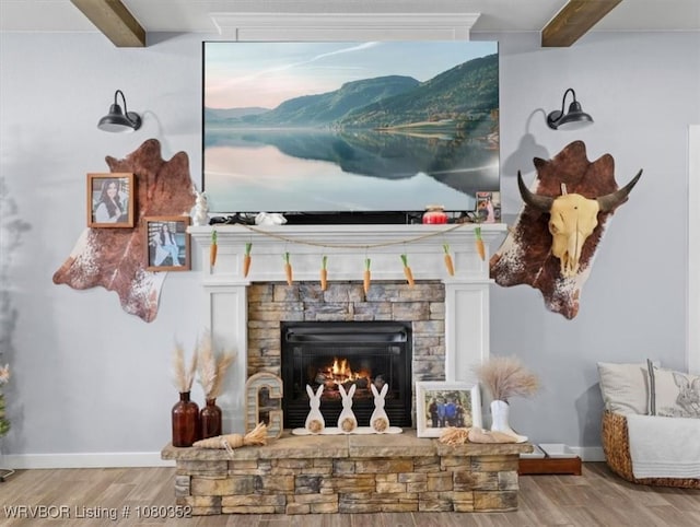details featuring wood finished floors, beam ceiling, baseboards, and a stone fireplace