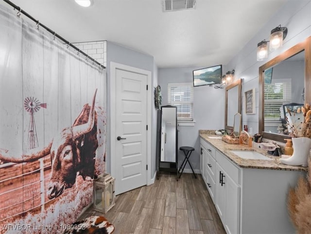 bathroom featuring double vanity, wood finished floors, visible vents, and a sink