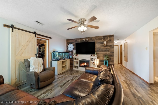 175 Sulphur City Rd, Fayetteville, AR 72701 - living room with wood finished floors, a barn door, a ceiling fan, a textured ceiling, and baseboards