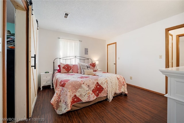 175 Sulphur City Rd, Fayetteville, AR 72701 - bedroom with dark wood-style flooring, a barn door, a textured ceiling, and baseboards