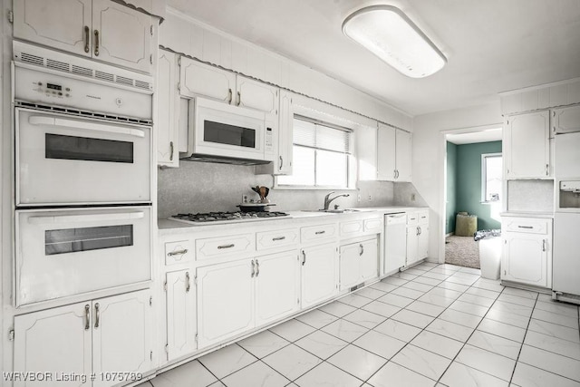 kitchen featuring white cabinetry, sink, white appliances, and backsplash