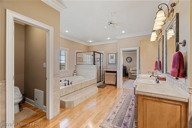 bathroom featuring tiled tub, hardwood / wood-style floors, vanity, ornamental molding, and toilet