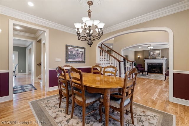 dining area with ornamental molding, an inviting chandelier, and light wood-type flooring