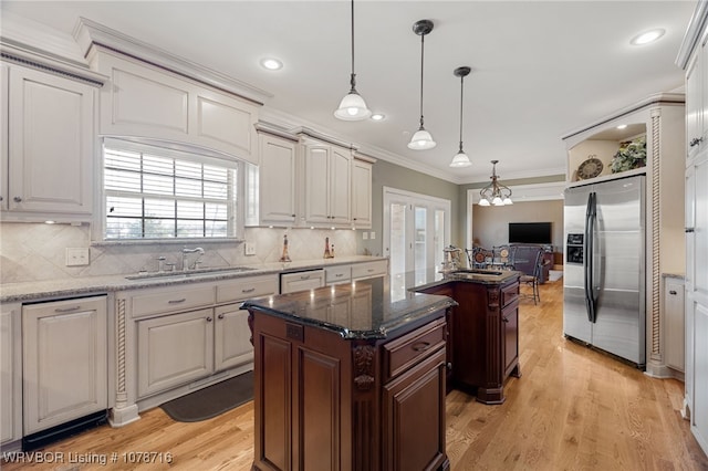 kitchen with sink, pendant lighting, stainless steel fridge, and dark stone counters