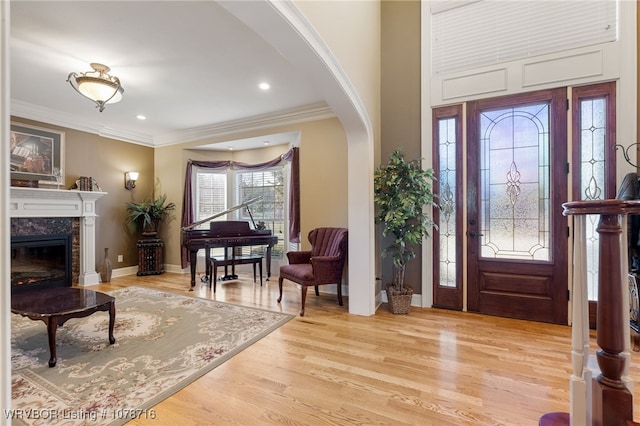 foyer entrance with crown molding, a high end fireplace, and light hardwood / wood-style flooring