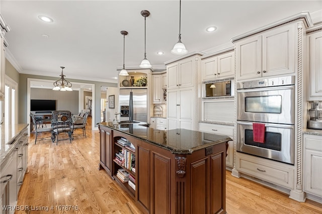 kitchen featuring stainless steel appliances, hanging light fixtures, dark stone countertops, and white cabinets