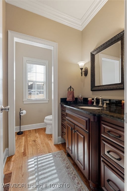 bathroom with vanity, hardwood / wood-style floors, ornamental molding, and toilet