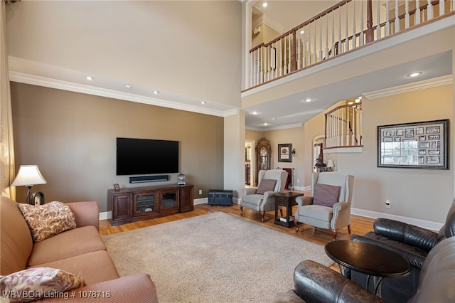 living room featuring crown molding, a towering ceiling, and light wood-type flooring