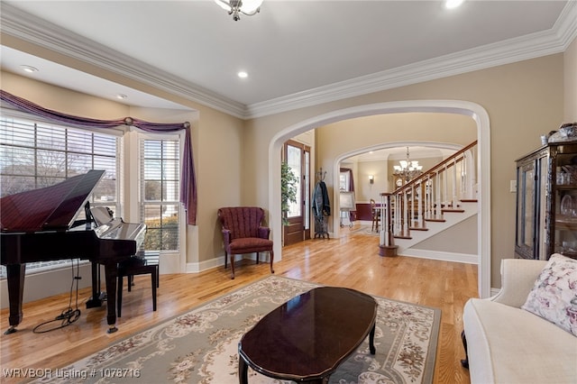 living area with crown molding, plenty of natural light, a notable chandelier, and light hardwood / wood-style flooring