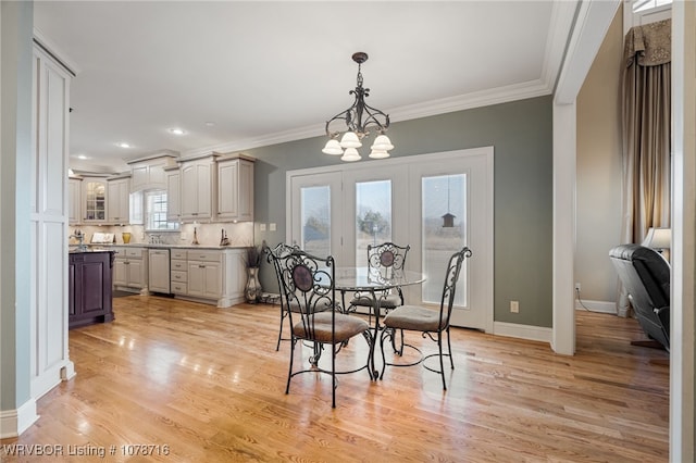 dining area with ornamental molding, a chandelier, sink, and light wood-type flooring