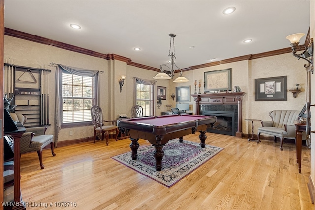 game room with pool table, a high end fireplace, light hardwood / wood-style flooring, and ornamental molding