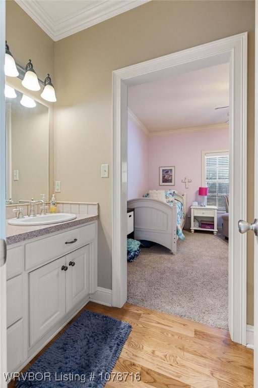 bathroom featuring ornamental molding, wood-type flooring, and vanity