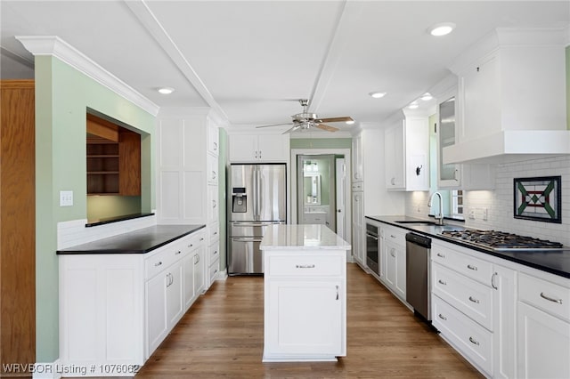 kitchen featuring appliances with stainless steel finishes, tasteful backsplash, premium range hood, sink, and a kitchen island