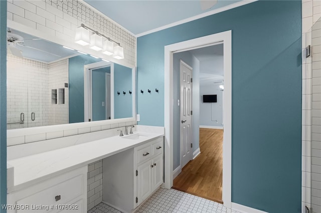 bathroom featuring vanity, a shower with door, crown molding, tile patterned flooring, and ceiling fan