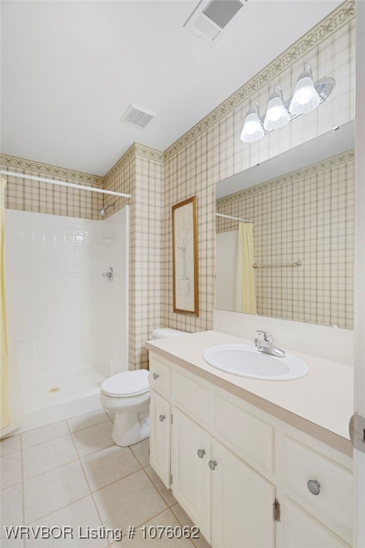 bathroom featuring tile patterned floors, vanity, toilet, and walk in shower