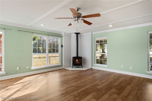 unfurnished living room featuring hardwood / wood-style flooring, a wood stove, ceiling fan, and crown molding