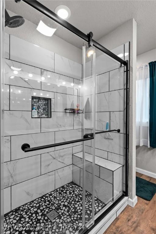 bathroom with hardwood / wood-style floors, a textured ceiling, and walk in shower