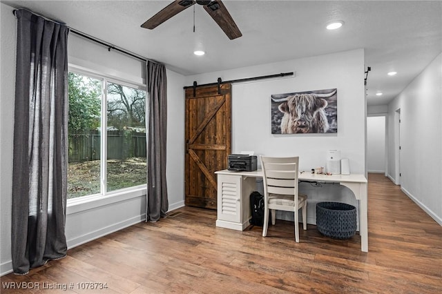 office area featuring dark hardwood / wood-style flooring, a barn door, and ceiling fan