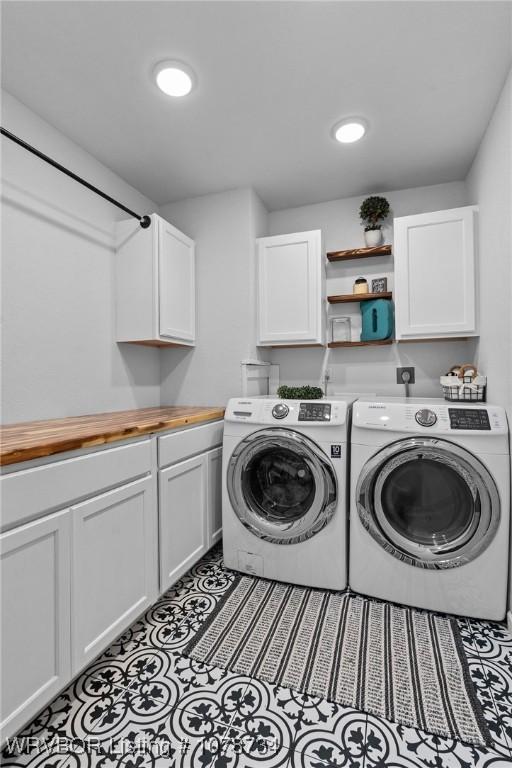 clothes washing area with cabinets, washing machine and dryer, and light tile patterned floors