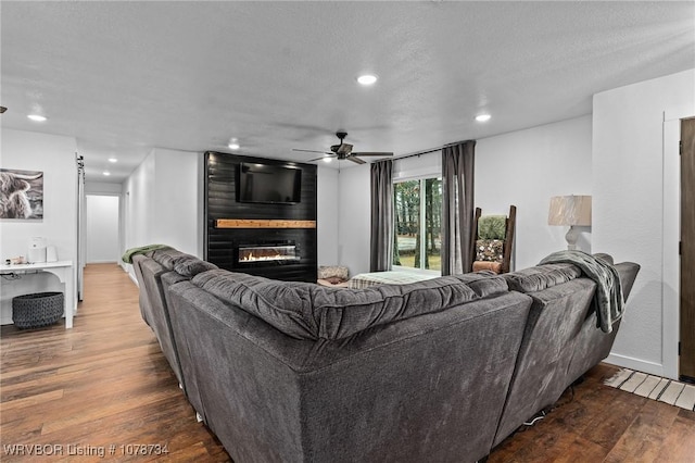 living room featuring a fireplace, ceiling fan, dark hardwood / wood-style floors, and a textured ceiling