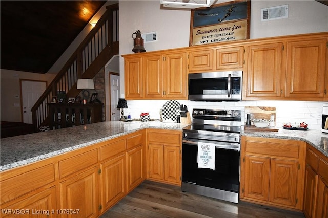 kitchen with dark hardwood / wood-style flooring, light stone counters, tasteful backsplash, and stainless steel appliances