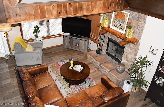 living room with wood-type flooring, a fireplace, and vaulted ceiling