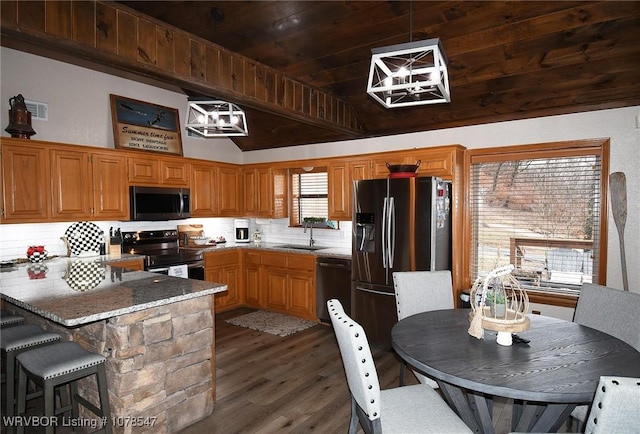 kitchen with appliances with stainless steel finishes, decorative light fixtures, tasteful backsplash, sink, and dark hardwood / wood-style flooring