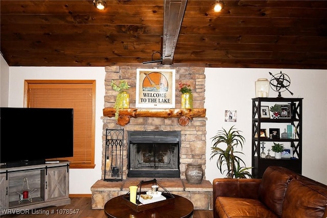 living room with vaulted ceiling with beams, a stone fireplace, wood-type flooring, and wooden ceiling