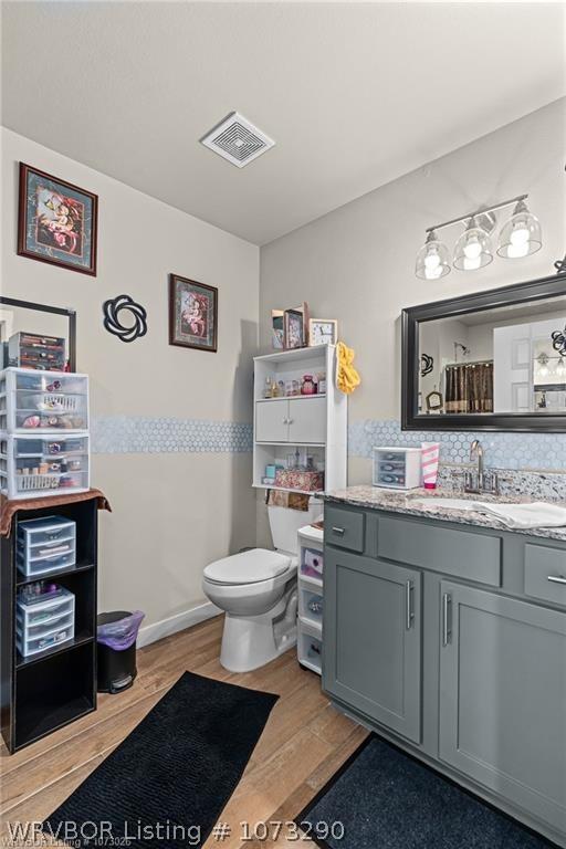 bathroom featuring decorative backsplash, hardwood / wood-style floors, vanity, and toilet