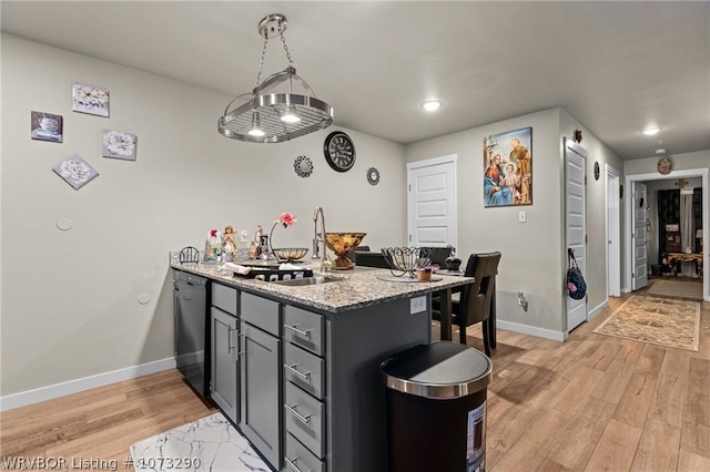 kitchen with kitchen peninsula, light stone countertops, light wood-type flooring, dishwasher, and hanging light fixtures