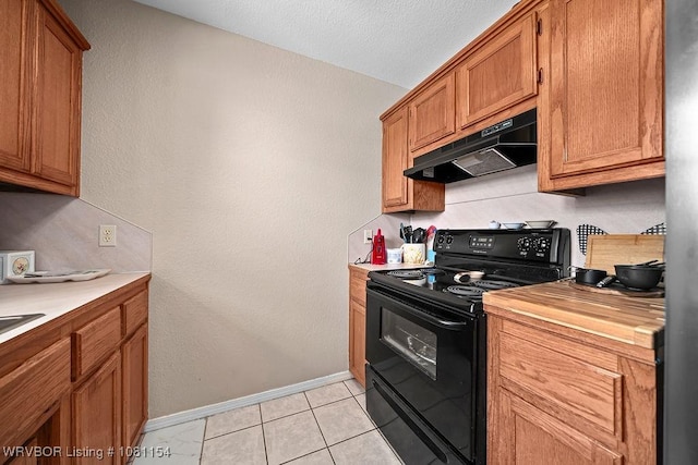 112179 S 4776th Rd, Muldrow, OK 74948 - kitchen with black range with electric stovetop, under cabinet range hood, baseboards, brown cabinetry, and light tile patterned floors