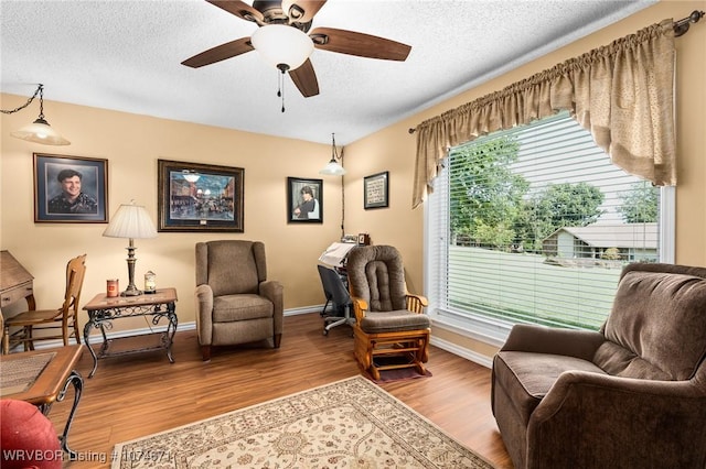 living area with hardwood / wood-style floors, a textured ceiling, and ceiling fan