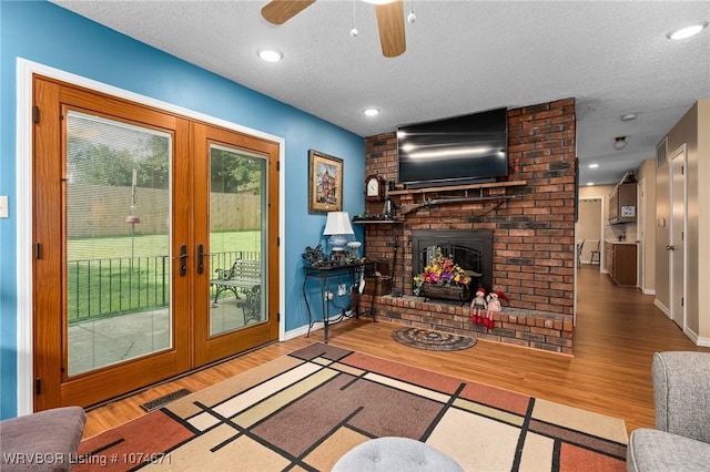 living room with a fireplace, french doors, wood-type flooring, and a textured ceiling