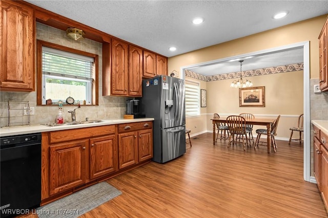 kitchen with stainless steel fridge, sink, decorative light fixtures, a notable chandelier, and black dishwasher