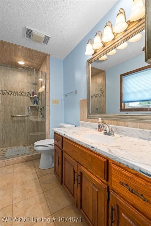 bathroom with walk in shower, tile patterned flooring, a textured ceiling, toilet, and vanity