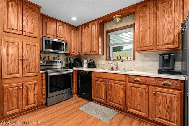 kitchen featuring backsplash, sink, light hardwood / wood-style flooring, and appliances with stainless steel finishes