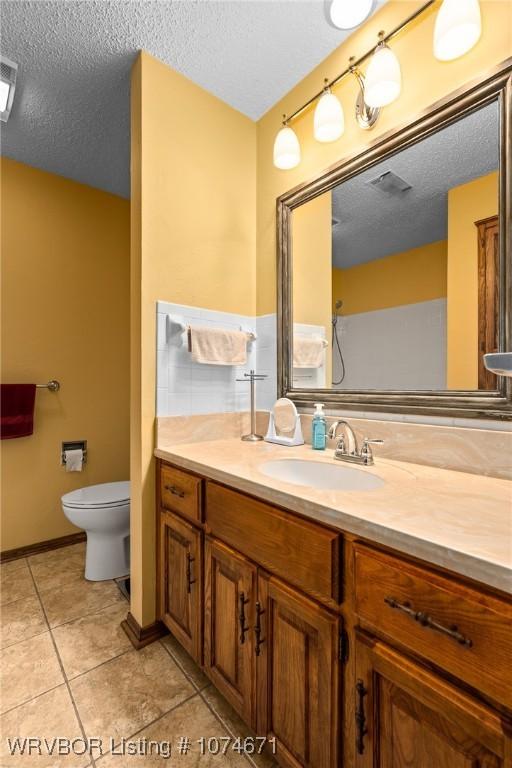 bathroom featuring tile patterned floors, vanity, a textured ceiling, and toilet