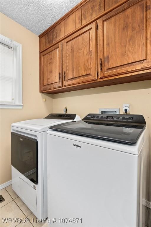 washroom with cabinets, light tile patterned floors, a textured ceiling, and separate washer and dryer