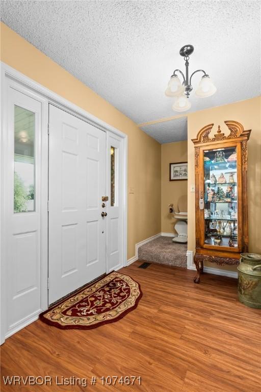 entryway featuring hardwood / wood-style floors, a notable chandelier, and a textured ceiling