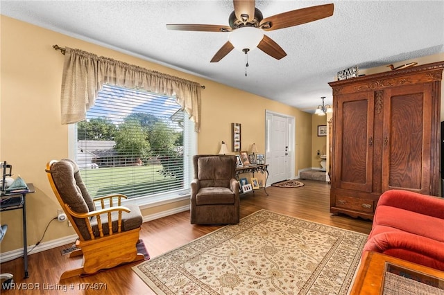 living area featuring wood-type flooring, a textured ceiling, and ceiling fan