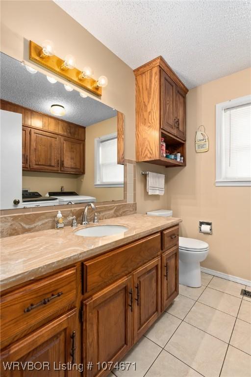 bathroom with tile patterned flooring, vanity, a textured ceiling, and toilet